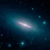 Длинный луч в центре представляет собой галактику NGC 5866 в профиль