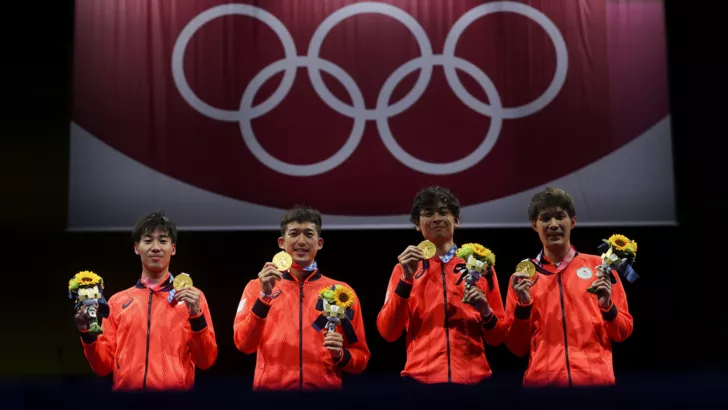 Золотые медалисты по фехтованию из Японии празднуют победу на пьедестале почета