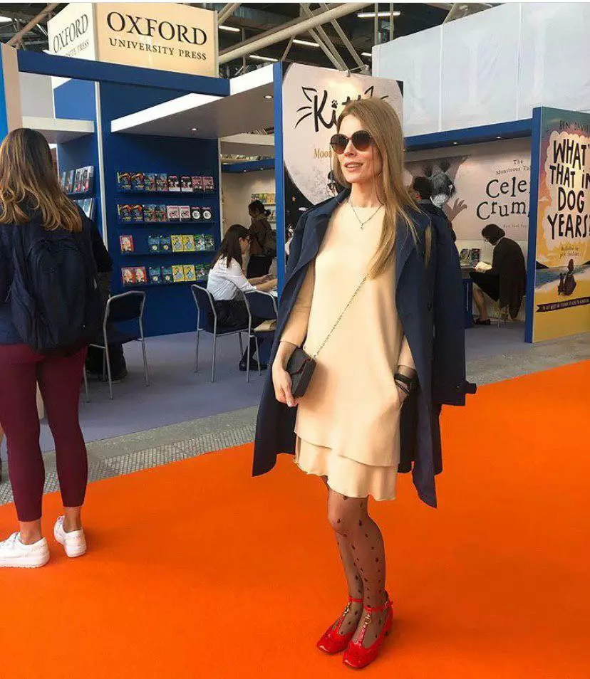 Ольга Фреймут в бежевом платье свободного кроя и темно-синем плаще посетила выставку в Италии