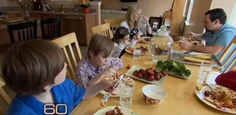 Кадр из программы "60 минут". Украинка сидит за столом вверху слева, рядом с приемной матерью