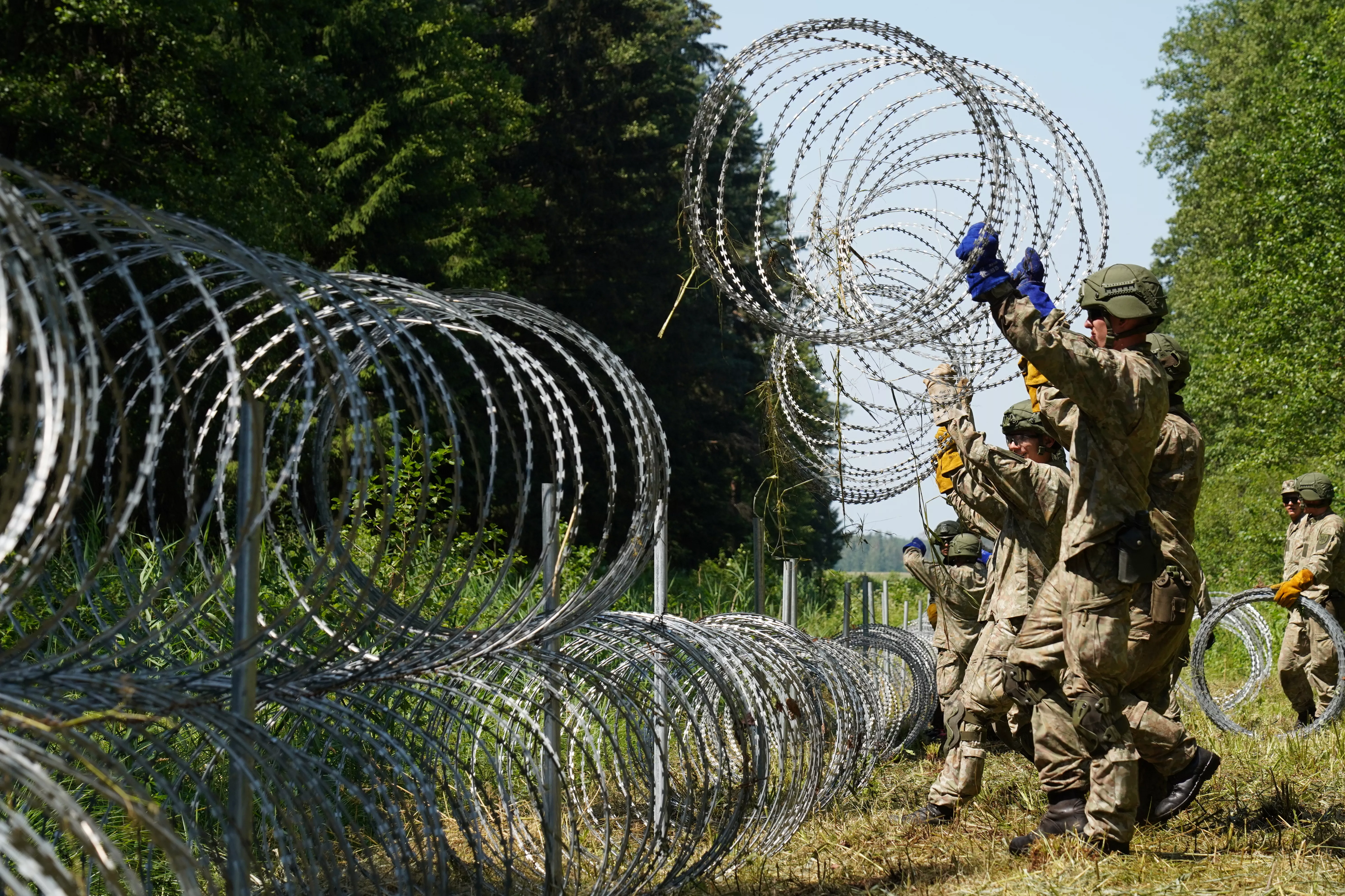 Литовські військові монтують стіну з колючого дроту. Фото: REUTERS/Janis Laizans