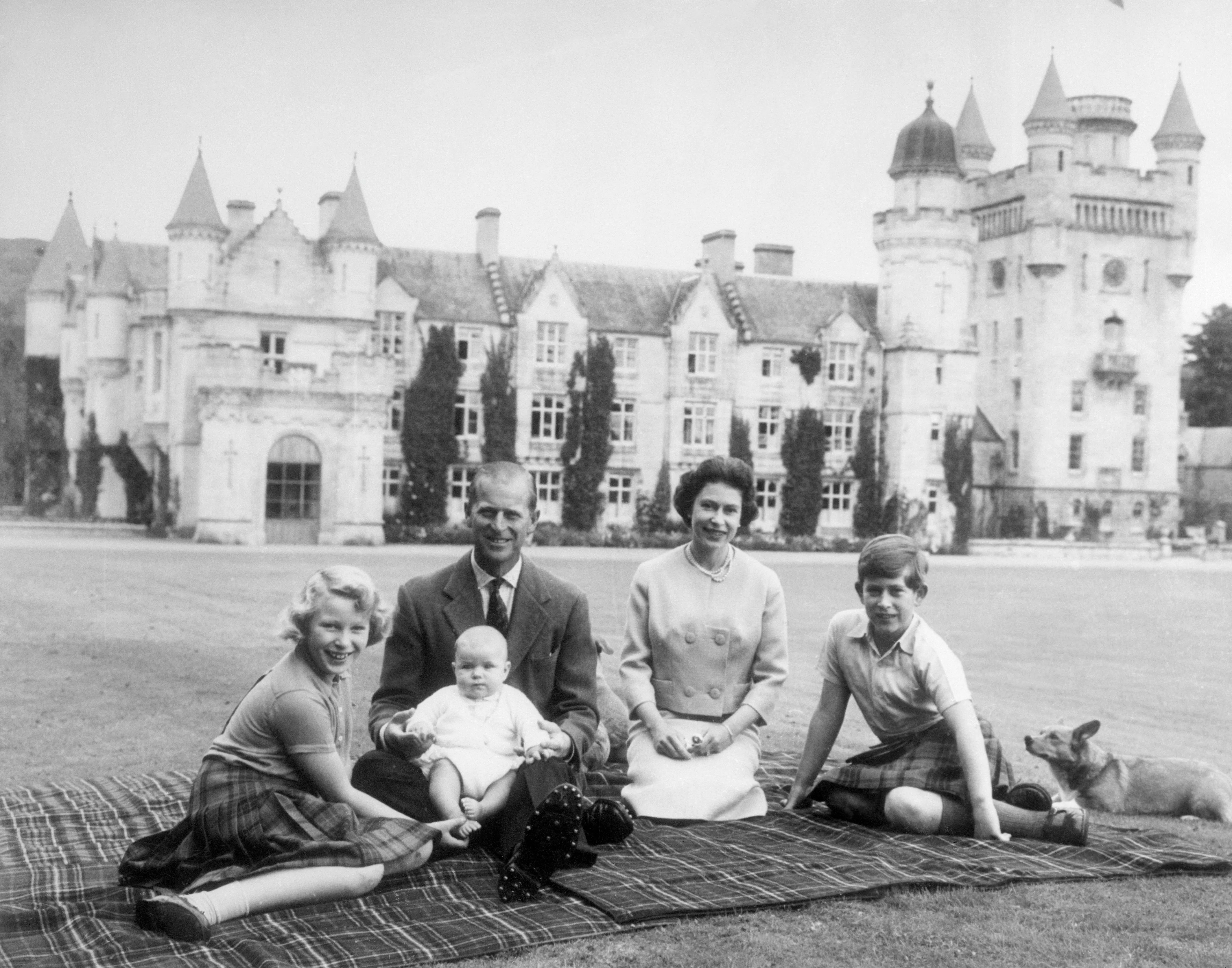 Принц Эндрю на руках у принца Филиппа, королева Елизавета, принц Чарльз и принцесса Анна на пикнике.