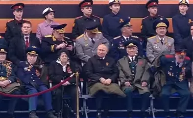 Путин, прочитав речь с листа бумаги, хромая вернулся на трибуну, и сидел, потупив взгляд, отрешенно рассматривая свои колени. Фото: скриншот