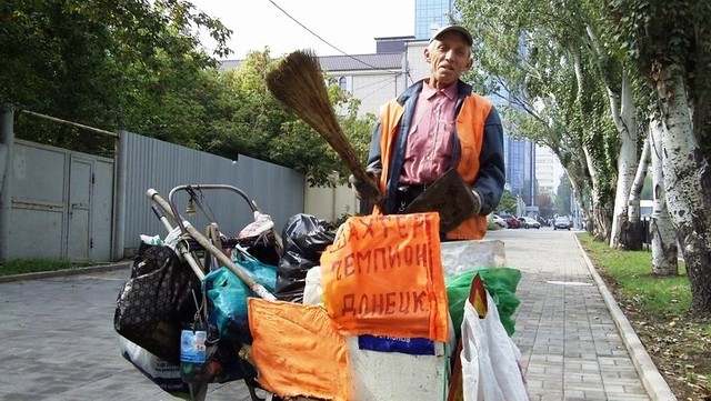 Дворник с тележкой занят уборкой на одной из улиц Донецка. Фото ostro.org