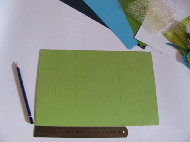 1. Кладем горизонтально цветной двусторонний картонный лист зеленого цвета формата А4, отмеряем с правого и левого краев сначала по 4,5 см, от этого расстояния — еще по 5,5 см. В результате посередине получится пространство в 10 см. Затем берем ножницы и под линейку очень аккуратно проводим линии по картону. Важно при этом сильно не давить на бумагу, чтобы потом можно было без лишних проблем согнуть картон необходимым нам образом.