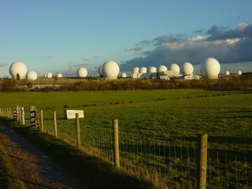 1. RAF Menwith Hill. Великобритания<br />
RAF Menwith Hill – британская военная база, связанная со всемирной шпионской сетью ЭШЕЛОН.<br />
На базе находятся наземные станции спутниковой связи, прослушивания телефонных разговоров и предупреждения о ракетном нападении. Она была описана как крупнейшая электронная станция мониторинга в мире. Место представляет собой наземную станцию со спутниками, оперируемыми американским разведывательным бюро от имени Американской службы безопасности. База также была задействована для отчетов касательно коммерческого шпионажа. <br />
