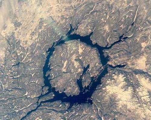 5. Маникуаган<br />
Кратер Маникуаган — ударный кратер в центральной части провинции Квебек, Канада, который сформировался в результате столкновения с астероидом диаметром 5 км. Удар астероида создал кратер около 100 км в диаметре, но в процессе эрозии и отложения осадочных пород видимый размер уменьшился до 71 км. Это пятый по величине известный кратер на Земле. Предполагается, что гора Вавилон является центральным пиком кратера. В настоящее время в кратере располагается озеро Маникуаган. Недавние исследования показали, что расплавленные в результате столкновения породы имеют возраст 214 млн. лет.<br />
