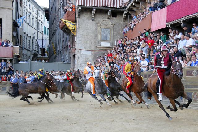 Італія. Двічі на рік на головній площі міста – Пьяцца дель Кампо – влаштовуються змагання на конях між 10 районами міста. Саме в Середні століття і зародилася традиція проводити в місті скачки, що отримали назву Сієнського Паліо. Історія свідчить, що перші скачки на конях пройшли в 1656 році, в цей та наступні роки скачки проходили тільки один раз на рік – 2 липня. Починаючи з 1701 роки, свято Паліо став проводитися двічі на рік – 2 липня і 16 серпня. Фото: AFP