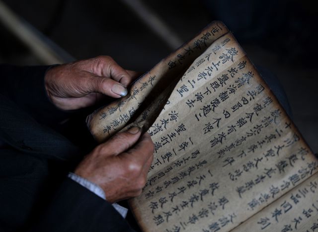 Китай. Местный шаман, листая старинную книгу, для всех желающих предсказывает будущее. Фото: AFP