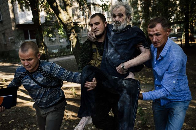 Украина. В Донецке молодые люди помогают мужчине покинуть место, обстреливаемое боевиками. Фото: AFP