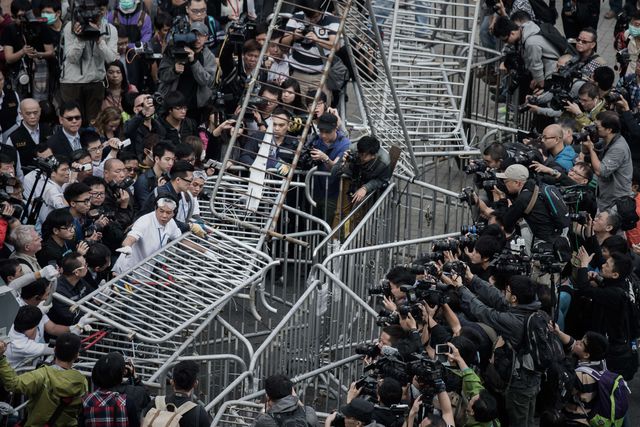 Десятки людей намагалися прорватися в будівлю уряду в Гонконзі. Штурм почався, після того як поліція знесла барикади демонстрантів на вулицях міста. В акції брали участь місцеві студенти, які майже два місяці страйкували, виступаючи за демократичні вибори в регіоні. Вони перевернули загородження і прийнялися бити скляні вітрини на першому поверсі. Фото: AFP