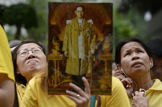 Лікуючі лікарі короля Таїланду Пхуміпхоном Адул'ядета (Рами Дев'ятого) скасували участь монарха в масових святкових заходах на честь його 87-річчя. Всю ніч на вулицях, що ведуть від лікарні до Палацу, збиралися люди з усіх кінців Таїланду, щоб вранці побажати монарху міцного здоров'я та привітати його з Днем народження під час проходження кортежу. Рішення лікарів фактично скасувало і аудієнцію, і масові поздоровлення на вулицях. Фото: AFP
