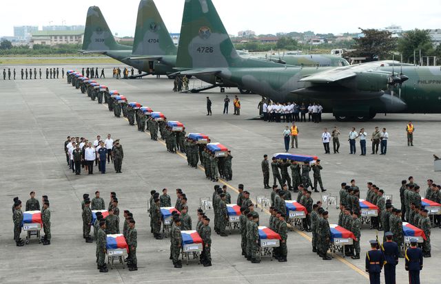 Филиппинские коммандос выносят драпированные национальными флагами гробы с телами своих товарищей из самолётов С-130 после их прибытия на военную базу в Маниле. Фото: AFP