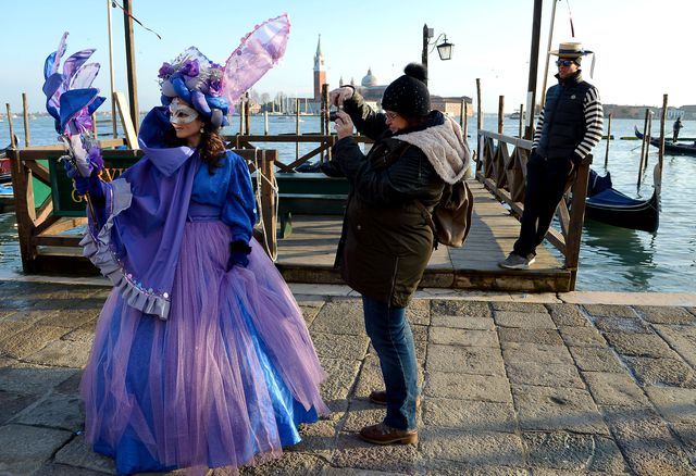 У Венеції проходить костюмоване свято – Венеціанський карнавал. На фото: артистка позує на камеру туристки недалеко від площі Святого Петра у Венеції. Фото: AFP