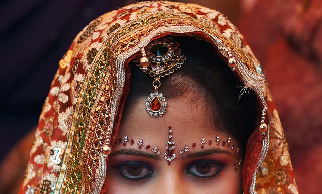 В Индии невеста ждет церемонии массового бракосочетания в местном храме. Двенадцать пар связали себя узами брака во время церемонии бракосочетания. Массовые свадебные церемонии в Индии организовываются, чтобы помочь тем, кто не может позволить себе традиционно большие свадьбы. Фото: AFP