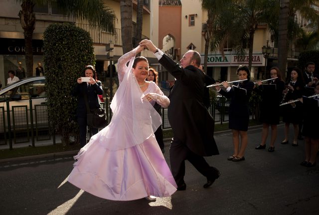 Люди в бальных нарядах танцуют во время уличного парада в Торремолиносе.  Фото: AFP