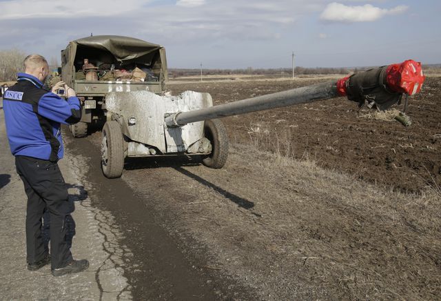 Українські військовослужбовці відводять важке озброєння від лінії розмежування під наглядом представників ОБСЄ. (Протитанкові гармати 100 мм МТ-12 "Рапіра") Фото: AFP
