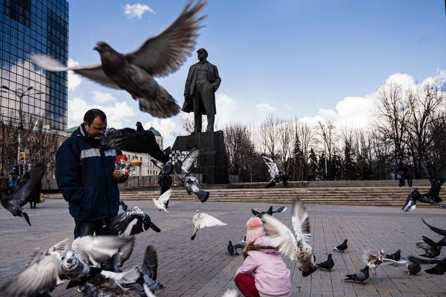 Мужчина с дочкой кормят голубей на площади у памятника Ленину в Донецке. Фото: AFP