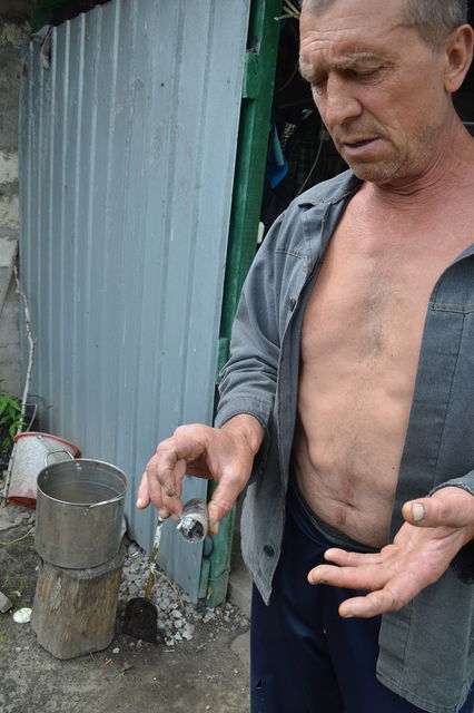 Хозяин показывает остатки гранаты из автоматического гранатомета, которая залетела и взорвалась у него во дворе. Фото: moskal.in.ua