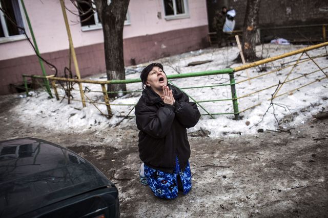 В Донбассе женщине после мощного обстрела Куйбышевского района просит на коленях прекратить обстрелы. Фото: AFP