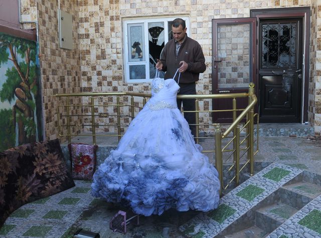 В Іраку батько тримає весільну сукню дочки, яку вона так і не змогла одягти – дівчина була вбита. Фото: AFP