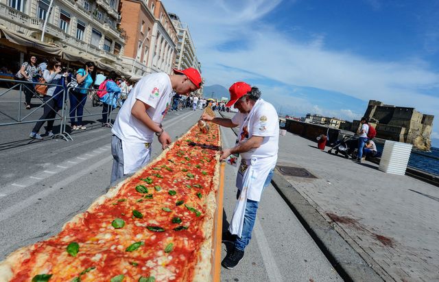 В італійському Неаполі спекли найдовший в світі піцу. Довжина страви склала тисячі вісімсот п'ятьдесят чотири метри. У рекорді брали участь 250 кухарів, які готували шість годин і 11 хвилин. Для того, щоб виконати задумане, італійським майстрам знадобилося: більше двох тисяч кілограмів борошна, 1,6 тисячі кілограмів томатів, дві тисячі кілограмів сиру моцарелла, двісті літрів оливкової олії та 30 кілограмів базиліка. Фото: AFP