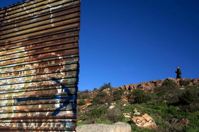 Американський прикордонник спостерігає за дірою в паркані на кордоні США і Мексики. Фото: AFP